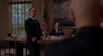 Movie still from “The Caine Mutiny Court-Martial” (2023), directed by William Friedkin – Two women in military uniforms in front of an american flag; Medium shot, Over the shoulder angle