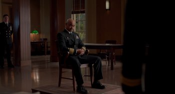 Movie still from “The Caine Mutiny Court-Martial” (2023), directed by William Friedkin – A man in a uniform sitting in a chair; Medium shot, Over the shoulder angle
