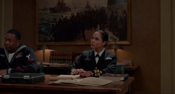 Movie still from “The Caine Mutiny Court-Martial” (2023), directed by William Friedkin – A woman sitting at a table in a room; Medium shot, Over the shoulder angle