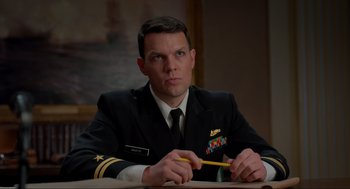 Movie still from “The Caine Mutiny Court-Martial” (2023), directed by William Friedkin – A man in a military uniform sitting at a table with a pencil; Close Up shot, Low angle