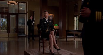 Movie still from “The Caine Mutiny Court-Martial” (2023), directed by William Friedkin – A woman in a uniform sitting on a chair in front of two other people; Wide shot, Low angle