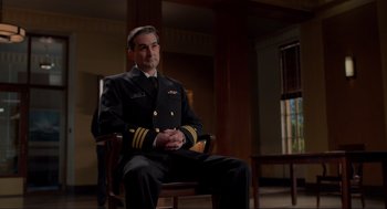 Movie still from “The Caine Mutiny Court-Martial” (2023), directed by William Friedkin – A man in a uniform sitting in a wooden chair; Medium shot, Low angle