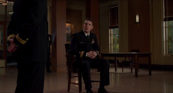 Movie still from “The Caine Mutiny Court-Martial” (2023), directed by William Friedkin – A man in a uniform sitting on a chair; Wide shot, Over the shoulder angle