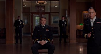 Movie still from “The Caine Mutiny Court-Martial” (2023), directed by William Friedkin – A man in a uniform sitting in a chair in front of another man in a uniform; Wide shot, Low angle