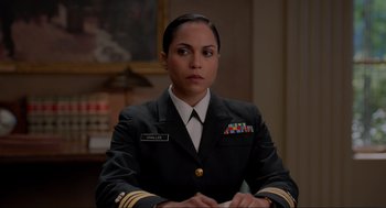 Movie still from “The Caine Mutiny Court-Martial” (2023), directed by William Friedkin – A woman in a uniform sitting at a table; Medium shot, Over the shoulder angle