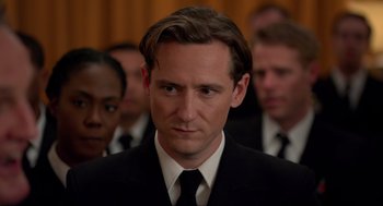 Movie still from “The Caine Mutiny Court-Martial” (2023), directed by William Friedkin – A man in a suit and tie in front of a group of people; Close Up shot, Over the shoulder angle
