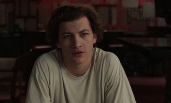 Movie still from “The Card Counter” (2021), directed by Paul Schrader – A young man in a white t - shirt is looking at the camera; Close Up shot, Low angle