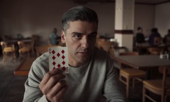 Movie still from “The Card Counter” (2021), directed by Paul Schrader – A man sitting at a table holding up a deck of cards; Close Up shot, Over the shoulder angle