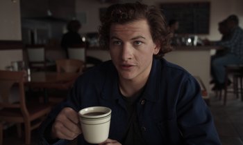 Movie still from “The Card Counter” (2021), directed by Paul Schrader – A man holding a cup of coffee while sitting at a table; Close Up shot, Low angle