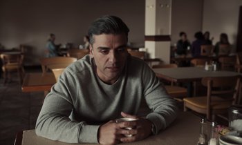 Movie still from “The Card Counter” (2021), directed by Paul Schrader – A man sitting at a table with a cup in his hand; Close Up shot, Over the shoulder angle