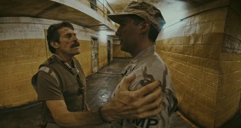 Movie still from “The Card Counter” (2021), directed by Paul Schrader – Two men are talking to each other in an alley; Medium shot, High angle