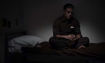 Movie still from “The Card Counter” (2021), directed by Paul Schrader – A man sitting on a bed in a dark room; Medium shot, Low angle