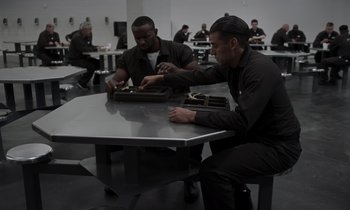 Movie still from “The Card Counter” (2021), directed by Paul Schrader – A group of men sitting at a table in a room; Medium shot, High angle