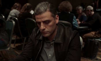 Movie still from “The Card Counter” (2021), directed by Paul Schrader – A man sitting at a table in front of a group of people; Close Up shot, Over the shoulder angle