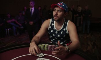 Movie still from “The Card Counter” (2021), directed by Paul Schrader – A man sitting at a poker table in a red room; Medium shot, High angle