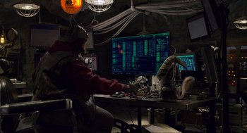 Movie still from “The Christmas Chronicles: Part Two” (2020), directed by Chris Columbus – A man sitting in front of a computer monitor; Wide shot, Over the shoulder angle