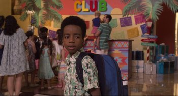 Movie still from “The Christmas Chronicles: Part Two” (2020), directed by Chris Columbus – A young boy with a backpack standing in front of a crowd of people; Medium shot, Over the shoulder angle