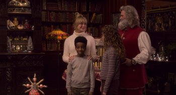 Movie still from “The Christmas Chronicles: Part Two” (2020), directed by Chris Columbus – A woman standing next to two children in a room; Medium shot, Over the shoulder angle