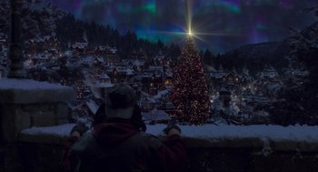 Movie still from “The Christmas Chronicles: Part Two” (2020), directed by Chris Columbus – A person sitting in front of a large christmas tree; Extreme Wide shot, Low angle