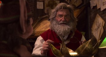 Movie still from “The Christmas Chronicles: Part Two” (2020), directed by Chris Columbus – An old man with a long white beard holding a gold plate; Close Up shot, Over the shoulder angle