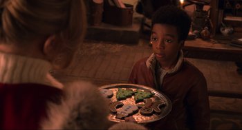 Movie still from “The Christmas Chronicles: Part Two” (2020), directed by Chris Columbus – A young boy holding a tray of christmas cookies; Close Up shot, Over the shoulder angle