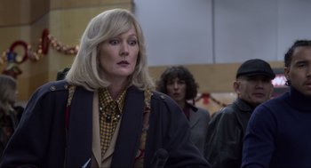 Movie still from “The Christmas Chronicles: Part Two” (2020), directed by Chris Columbus – A woman in a crowd of people in a room; Close Up shot, Over the shoulder angle