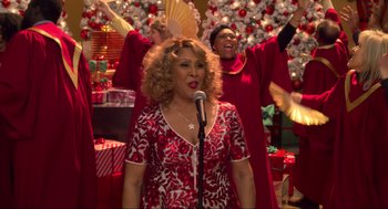Movie still from “The Christmas Chronicles: Part Two” (2020), directed by Chris Columbus – A group of women singing in front of a christmas tree; Medium shot, Over the shoulder angle