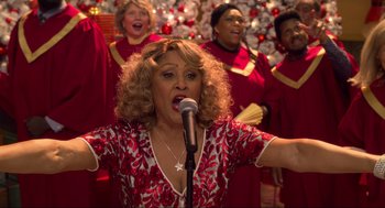 Movie still from “The Christmas Chronicles: Part Two” (2020), directed by Chris Columbus – A group of women singing in front of a christmas tree; Medium shot, High angle