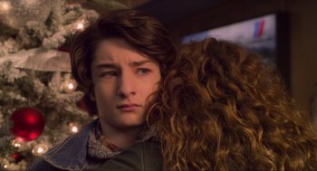 Movie still from “The Christmas Chronicles: Part Two” (2020), directed by Chris Columbus – A young man and a young woman embracing each other in front of a christmas tree; Close Up shot, Over the shoulder angle