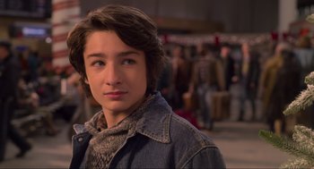Movie still from “The Christmas Chronicles: Part Two” (2020), directed by Chris Columbus – A young man in a denim jacket and a scarf; Close Up shot, Over the shoulder angle