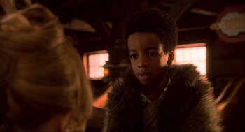 Movie still from “The Christmas Chronicles: Part Two” (2020), directed by Chris Columbus – A young boy wearing a fur coat looking at the camera; Close Up shot, Over the shoulder angle