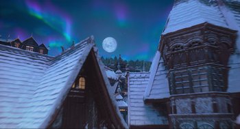 Movie still from “The Christmas Chronicles: Part Two” (2020), directed by Chris Columbus – A full moon is seen in the night sky above a snowy rooftops; Extreme Wide shot, Low angle