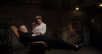 Movie still from “Crimes of the Future” (2022), directed by David Cronenberg – A man and a woman sitting on a chair; Medium shot, High angle
