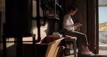 Movie still from “Crimes of the Future” (2022), directed by David Cronenberg – A man sitting on a chair in a room; Wide shot, Low angle