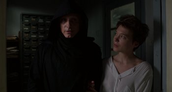 Movie still from “Crimes of the Future” (2022), directed by David Cronenberg – A man and a woman standing next to each other in a dark room; Medium shot, Low angle