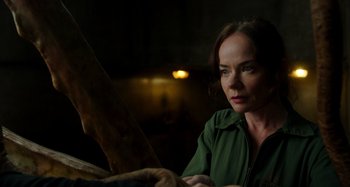 Movie still from “Crimes of the Future” (2022), directed by David Cronenberg – A woman sitting in front of an object in a dark room; Close Up shot, Low angle