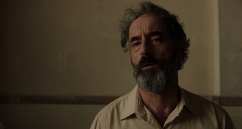 Movie still from “Crimes of the Future” (2022), directed by David Cronenberg – A man with a gray beard is standing in a room; Close Up shot, Low angle