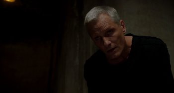 Movie still from “Crimes of the Future” (2022), directed by David Cronenberg – An older man in a black t - shirt looks at the camera; Close Up shot, High angle