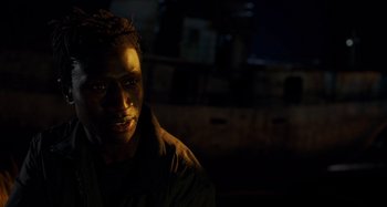 Movie still from “Crimes of the Future” (2022), directed by David Cronenberg – A man in a black shirt is in the dark; Close Up shot, Over the shoulder angle