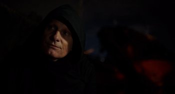 Movie still from “Crimes of the Future” (2022), directed by David Cronenberg – A man wearing a black hooded jacket looking at the camera; Close Up shot, Low angle