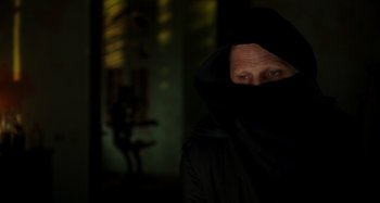 Movie still from “Crimes of the Future” (2022), directed by David Cronenberg – A man in a black hooded jacket is looking at the camera; Close Up shot, Low angle