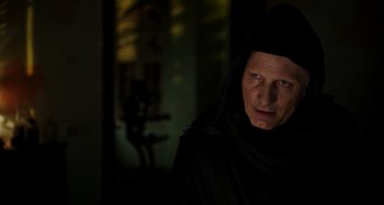Movie still from “Crimes of the Future” (2022), directed by David Cronenberg – An older man in a black robe and a black hood; Close Up shot, Low angle