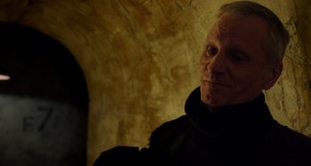 Movie still from “Crimes of the Future” (2022), directed by David Cronenberg – An older man in a black robe looking at the camera; Close Up shot, Over the shoulder angle