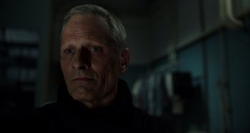 Movie still from “Crimes of the Future” (2022), directed by David Cronenberg – An older man in a black jacket looking at the camera; Close Up shot, Low angle