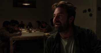 Movie still from “Crimes of the Future” (2022), directed by David Cronenberg – A man with a goatee is sitting at a table; Close Up shot, Over the shoulder angle