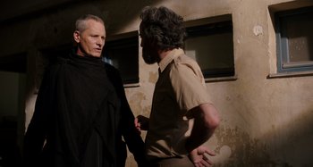 Movie still from “Crimes of the Future” (2022), directed by David Cronenberg – Two men talking to each other in front of a building; Medium shot, Over the shoulder angle