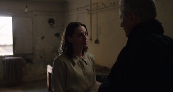 Movie still from “Crimes of the Future” (2022), directed by David Cronenberg – A woman and a man are talking in a dark room; Medium shot, Over the shoulder angle