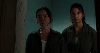 Movie still from “Crimes of the Future” (2022), directed by David Cronenberg – Two women standing next to each other near a wall; Close Up shot, Low angle