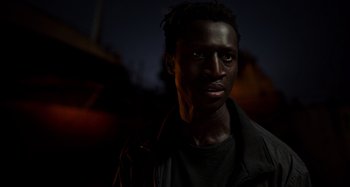 Movie still from “Crimes of the Future” (2022), directed by David Cronenberg – A man with dreadlocks standing in the dark at night; Close Up shot, Low angle