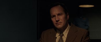 Movie still from “The Conjuring: The Devil Made Me Do It” (2021), directed by Michael Chaves – A man wearing a suit and tie in the dark; Close Up shot, Over the shoulder angle